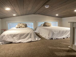 Ein Schlafzimmer mit zwei Betten, Holzboden und einer an der Decke befestigten Überwachungskamera.