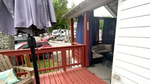 A wooden deck with a red railing, a bench, and a covered area with a sofa. - Sunrise Cottage at River Rocks Landing (Gadsden)