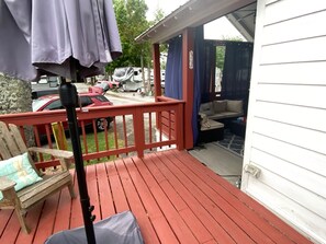 A wooden deck with a red railing, a bench, and a covered area with a sofa.