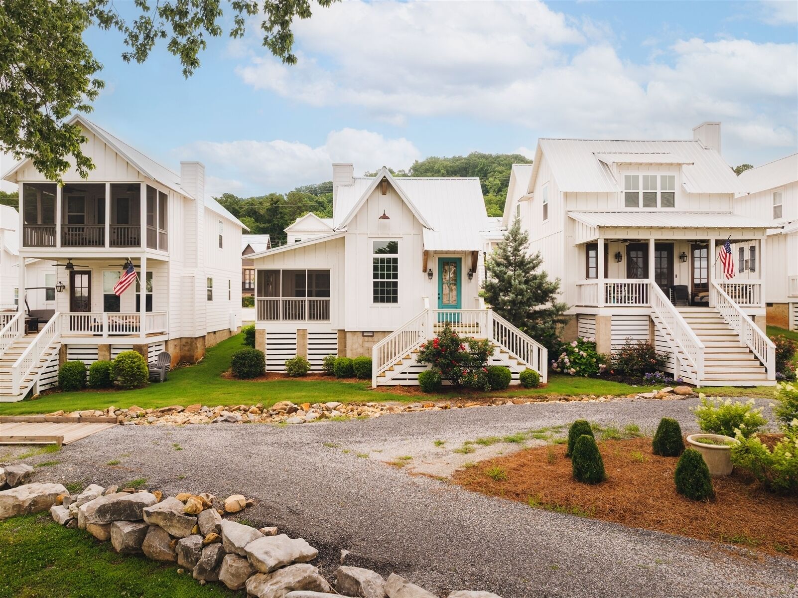 A row of white cabins with front porches, a central door, and a flag.