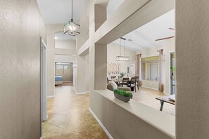 A spacious hallway with a dining area, a kitchen, and a bedroom. - Zona Resort 4-Bedroom House with Private Pool in the Estrella Mountains (Goodyear)