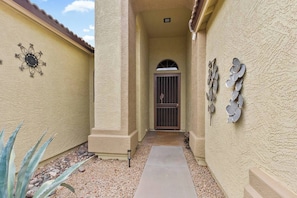 A narrow pathway leading to a gated entrance with a decorative metal gate and a small arched window.