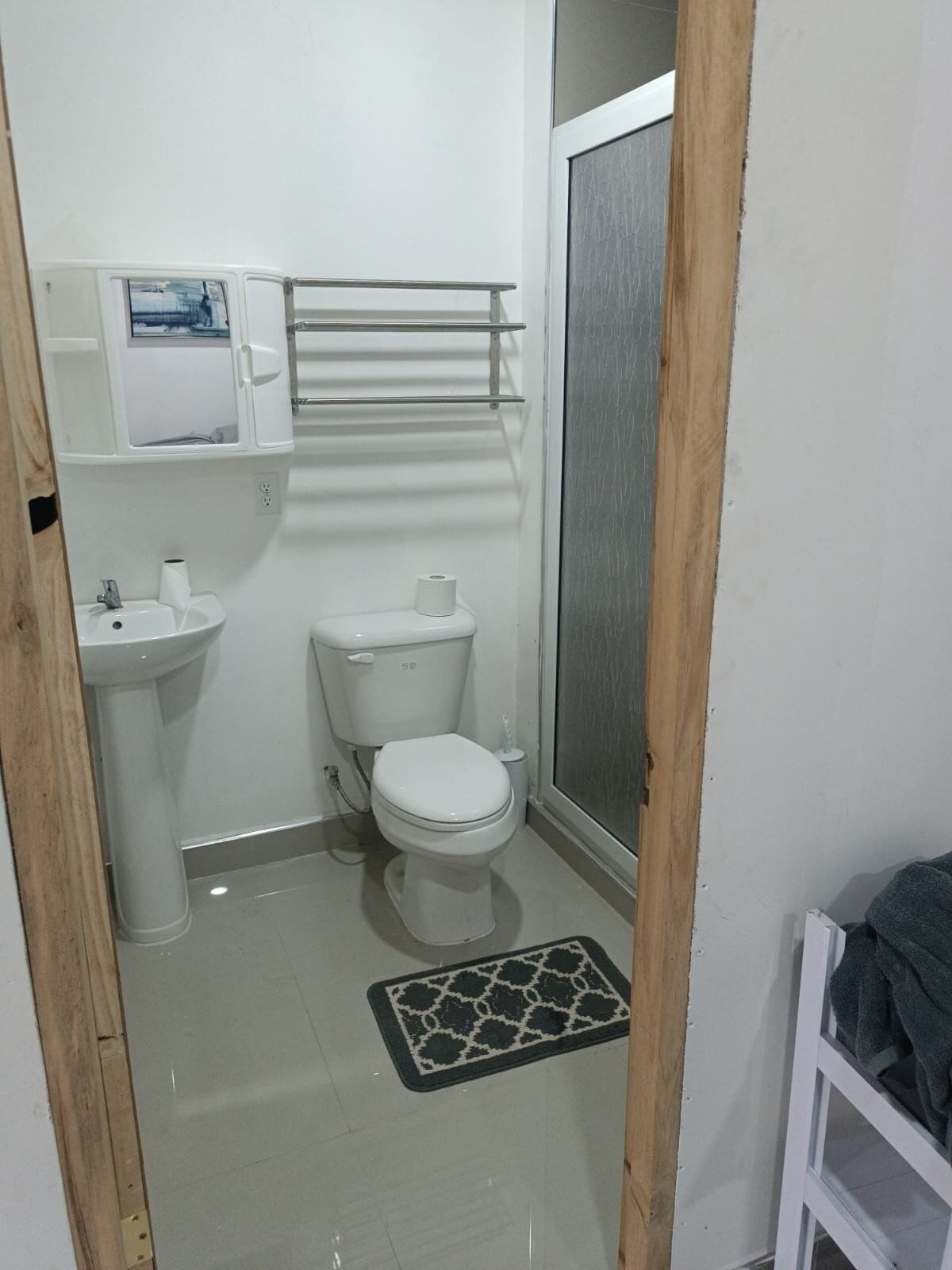 A small bathroom with a toilet, sink, and a shower area.