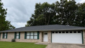 A single-story house with a garage, a front lawn, and a driveway. - Kimberly House (Mena)