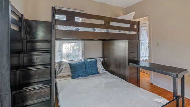 Una cama litera con escritorio, cajones y ventana con cortinas.