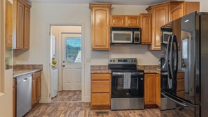 Una cocina con armarios de madera, un refrigerador de acero inoxidable, un microondas, un horno y un lavavajillas.