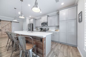 A modern kitchen with a central island, stainless steel appliances, and pendant lighting. - Coral Barracks at Lost Key Golf & Beach Club | Resort Amenities | My Beach Getaways (Pensacola)