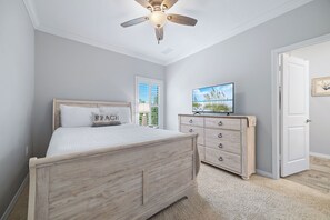 Ein Schlafzimmer mit Bett, Kommode, Fernseher und einer Tür.
