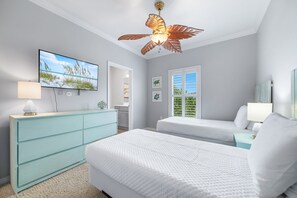 Ein Schlafzimmer mit zwei Betten, einem Fernseher, einem Deckenventilator und Blick ins Freie durch ein Fenster.