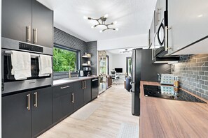 A modern kitchen with a Bosch oven, a built-in dishwasher, and a black-tiled backsplash.
