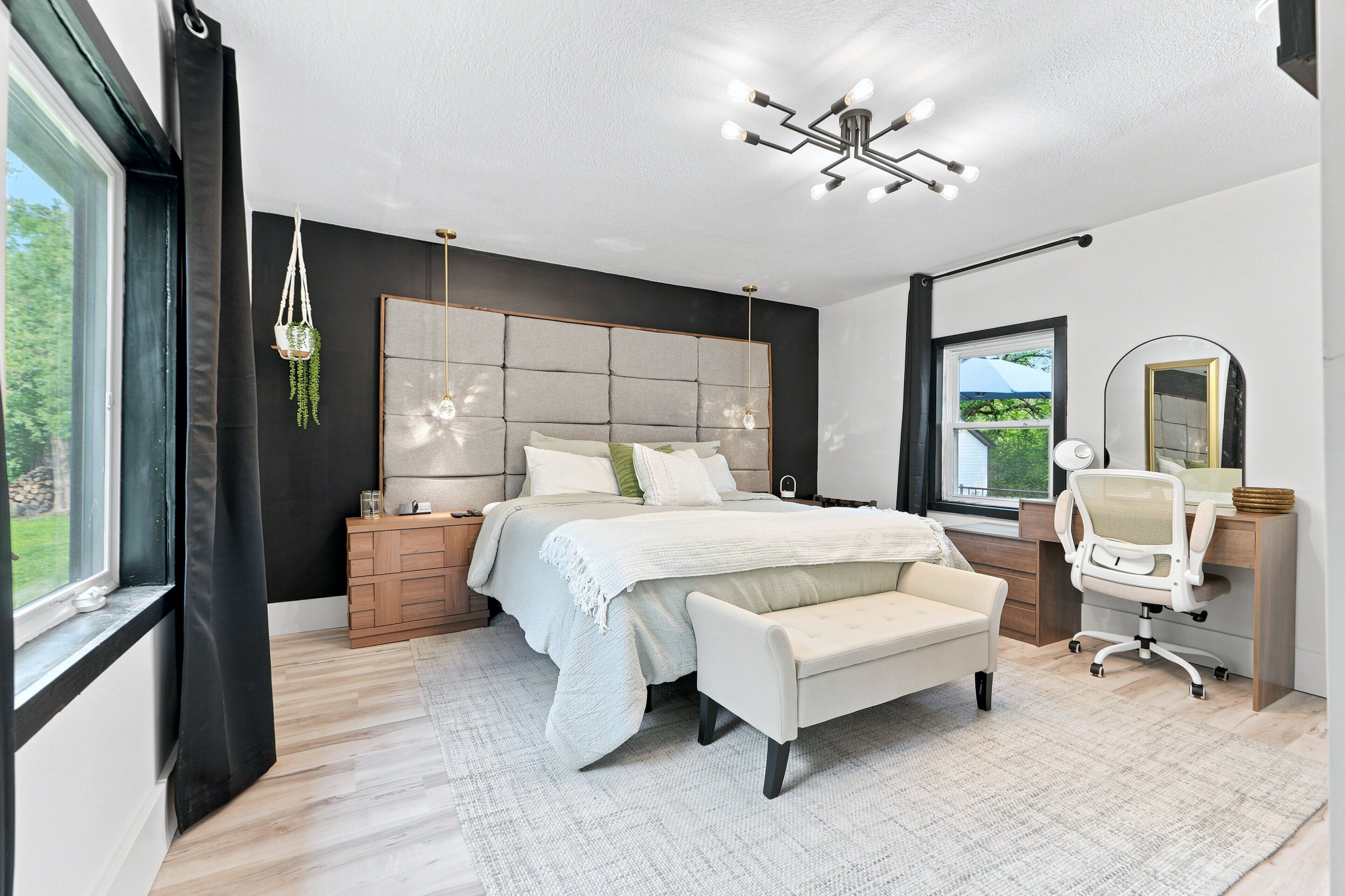 A modern bedroom with a large bed, bedside tables, a desk, and a chair.