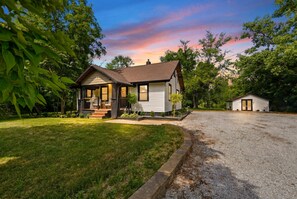 A two-story house with a front porch, a driveway, and a well-maintained lawn. - Luxury Designer Retreat on 1.3 Acres with Game Lounge (Fort Wayne)