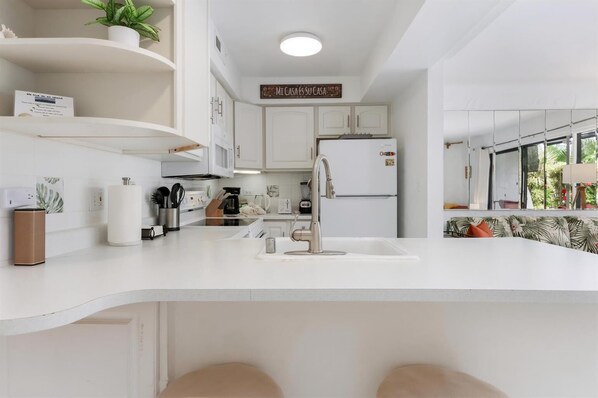 Eine moderne Küche mit weißen Schränken, einer eingebauten Spüle und einem Kühlschrank.