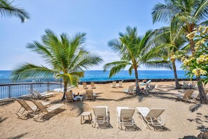 Ein Strand mit Liegestühlen, Palmen und Blick auf den Ozean.
