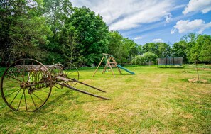 Ein grünes Freigelände mit Schaukel, Rutsche und einer großen, rostigen Metallkonstruktion.