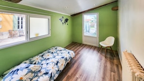 A room with a bed, a chair, a window, and a radiator. - Charmante maison avec piscine (Saint-Simon-de-Bordes)