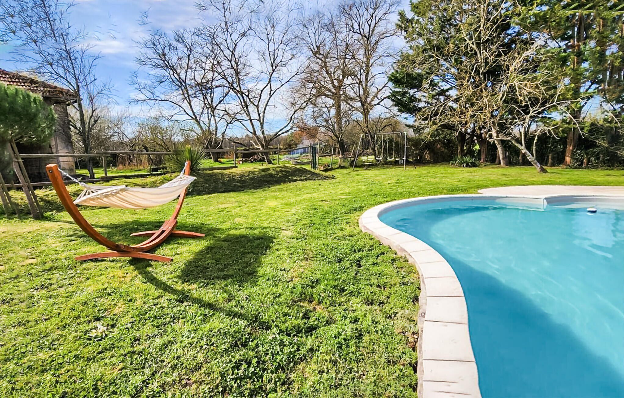 Un pati amb una piscina, una cadira espanyola i una zona enjardinada.