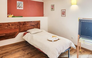 A single bed with a wooden headboard, a small bedside table, and a wall-mounted shelf. - harmant gîte au calme (Saint-Maigrin)