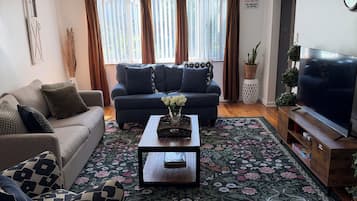 Una sala de estar con sofá, mesa de centro, televisor y alfombra estampada.