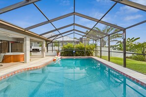A swimming pool with a covered patio area, a barbecue setup, and a view of a residential neighborhood. - Waterfront - Heated Pool - Dock - Gulf Access - Bring Your Boat (Port Charlotte)
