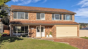 A two-story brick house with a garage, a covered front porch, and a well-maintained lawn. - Callow Place 10 - town location, relaxation, easy coastal living, Wifi (Bermagui)
