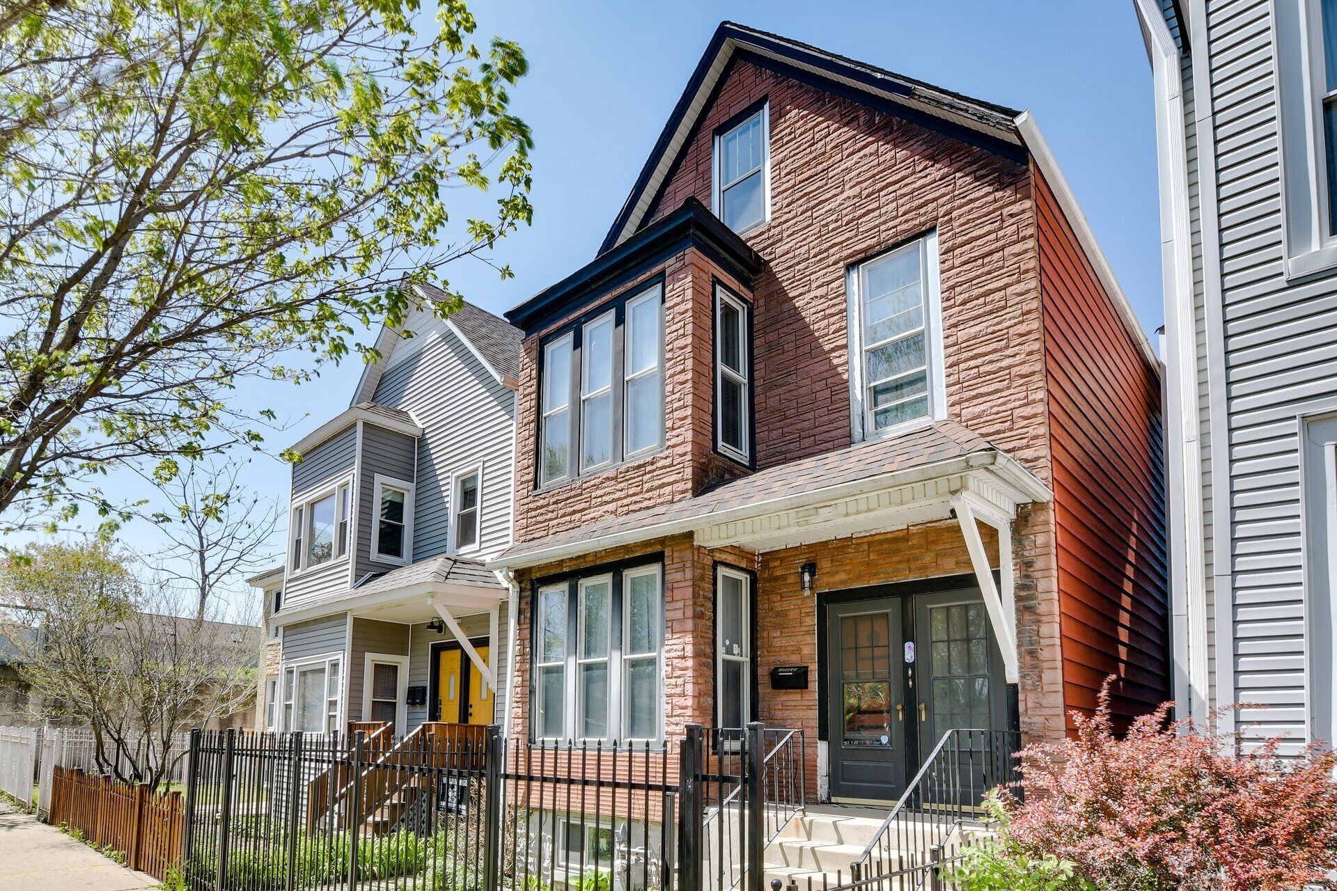 A two-story residential building with a brick facade, large windows, and a front porch.