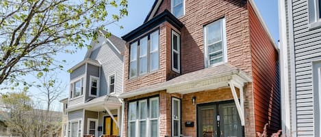 A two-story residential building with a brick facade, large windows, and a front porch.