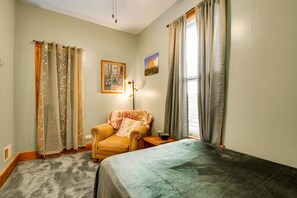 A room with a bed, a chair, a table, a lamp, and two windows with curtains. - Spacious 3-bedroom apartment in brilliant Chicago with AC Logan Square area, (Chicago)