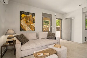 A modern living room with a sofa, a coffee table, and a painting on the wall. - Isichia Apartment with Sea and Taygetos Mountain Views (West Mani)
