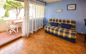 Ein Zimmer mit blauer Wand, einem Karosobensofa, einem kleinen Tisch mit kariertem Tuch und einem Sessel.
