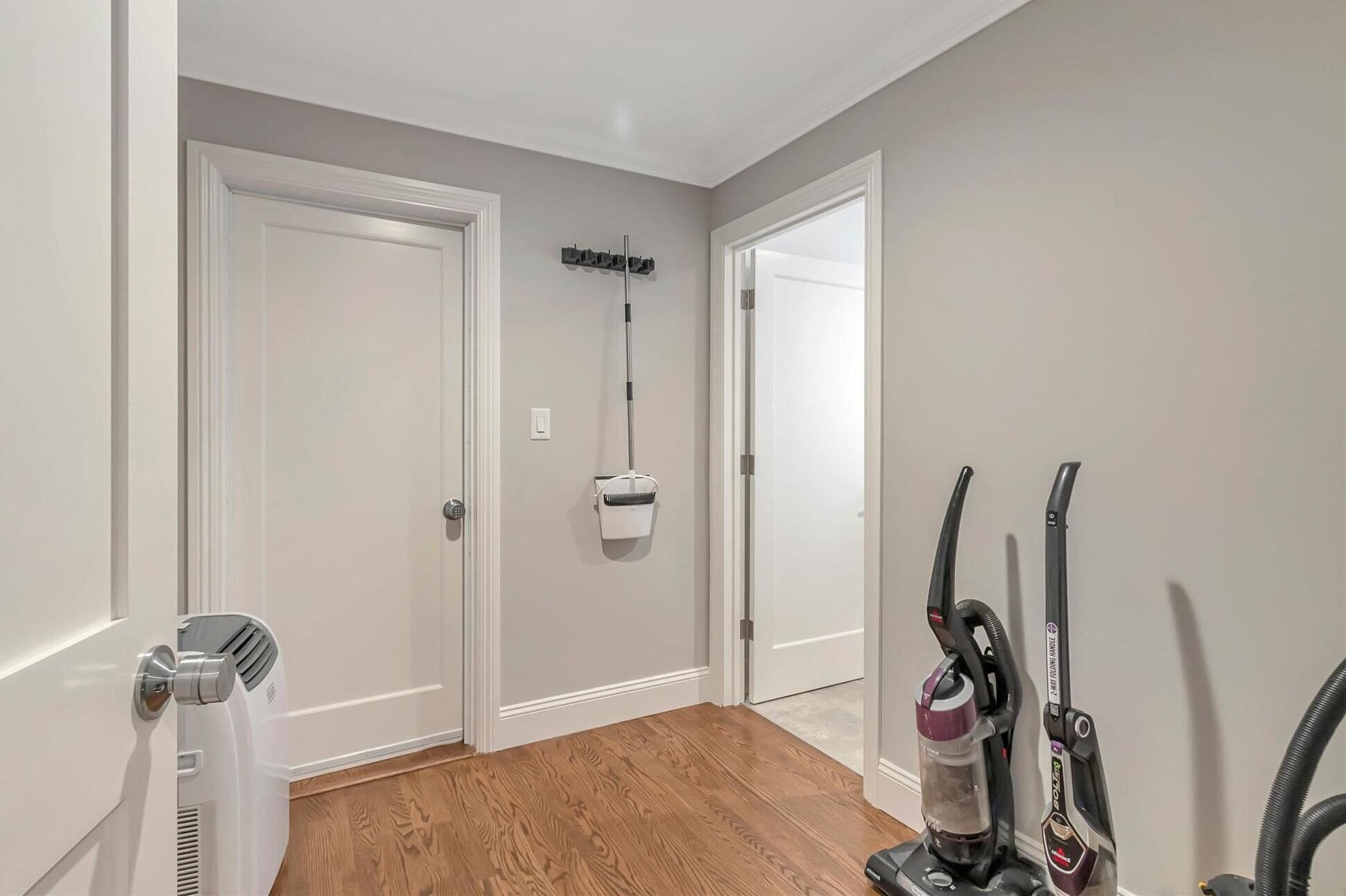 Un pasillo con dos puertas blancas, un aspirador y una lámpara de pared.