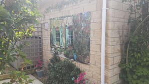 A brick wall with a window, potted plants, and a wooden fence. - Sleeps6-Garden-SummerHouse-Cotswolds-Bungalow (Stroud)