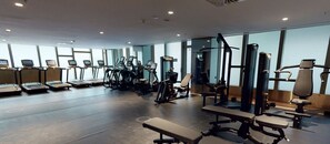 Ein Fitnessstudio mit Laufbändern, Kraftgeräten und Bänken.
