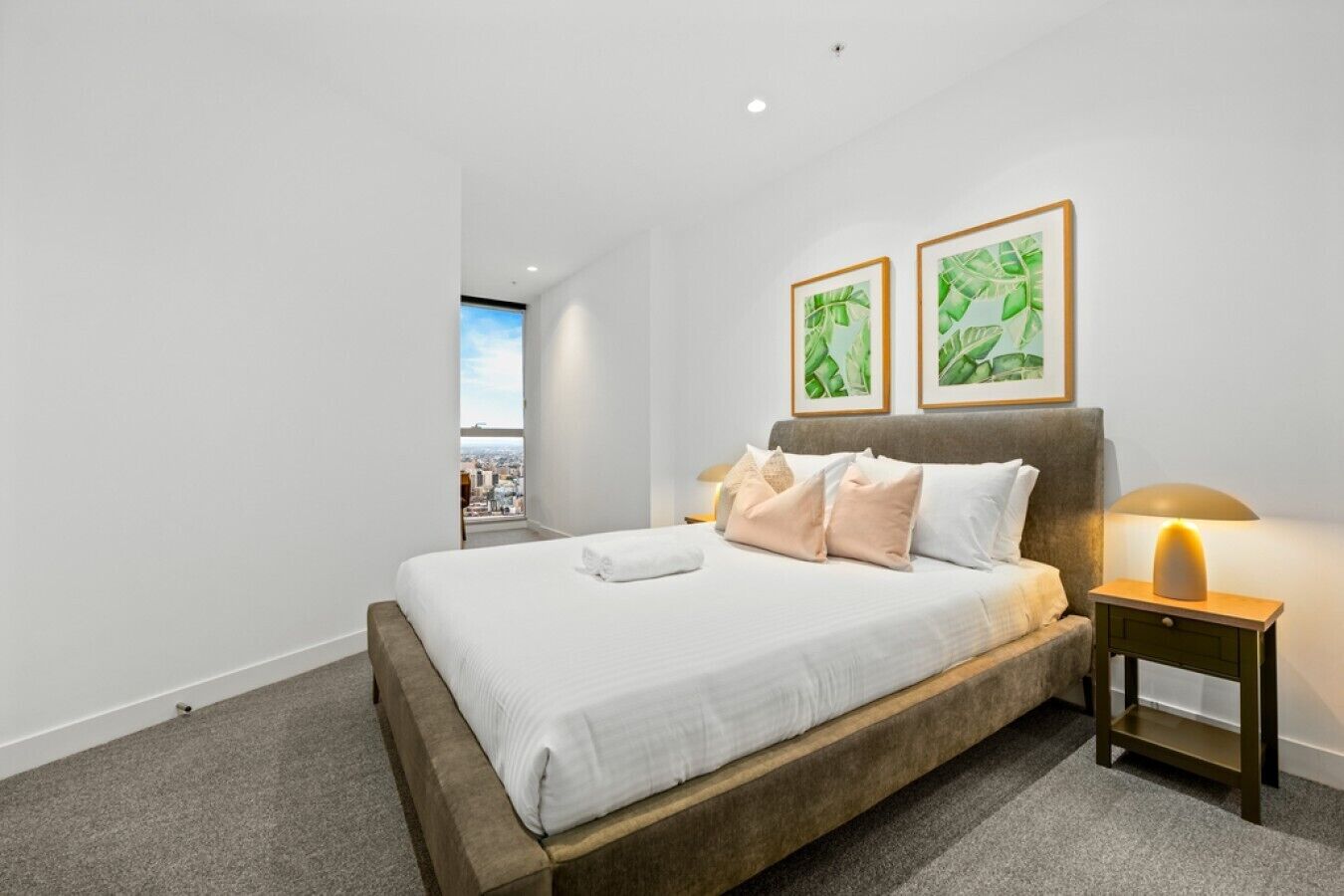 Ein Hotelzimmer mit einem großen Bett, einem Nachttisch mit Lampe und zwei gerahmten Bildern an der Wand.