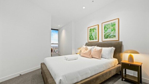 Een hotelkamer met een groot bed, een nachtkastje met lamp en twee ingelijste foto's aan de muur.