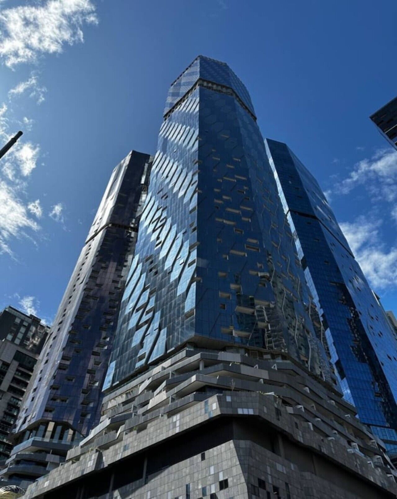 Un edificio de gran altura con un diseño angular distintivo y fachada de vidrio reflectante.