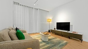 Een moderne woonkamer met een bank, een salontafel, een televisie en een lamp.