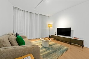 Ein modernes Wohnzimmer mit einer Couch, einem Couchtisch, einem Fernseher und einer Lampe.