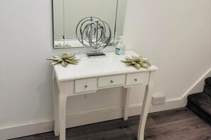 A white vanity with a mirror, two drawers, and decorative flowers.