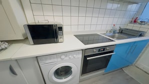 Eine kleine Küche mit Mikrowelle, Herd, Spüle und Waschmaschine.