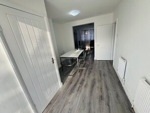 A room with a dining table and chairs, a white door, and a radiator.
