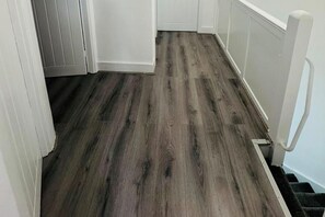 A hallway with a wooden floor and white walls. - Romford 4-Bed Home, Sleeps 7 with Garden & Parking (Romford)