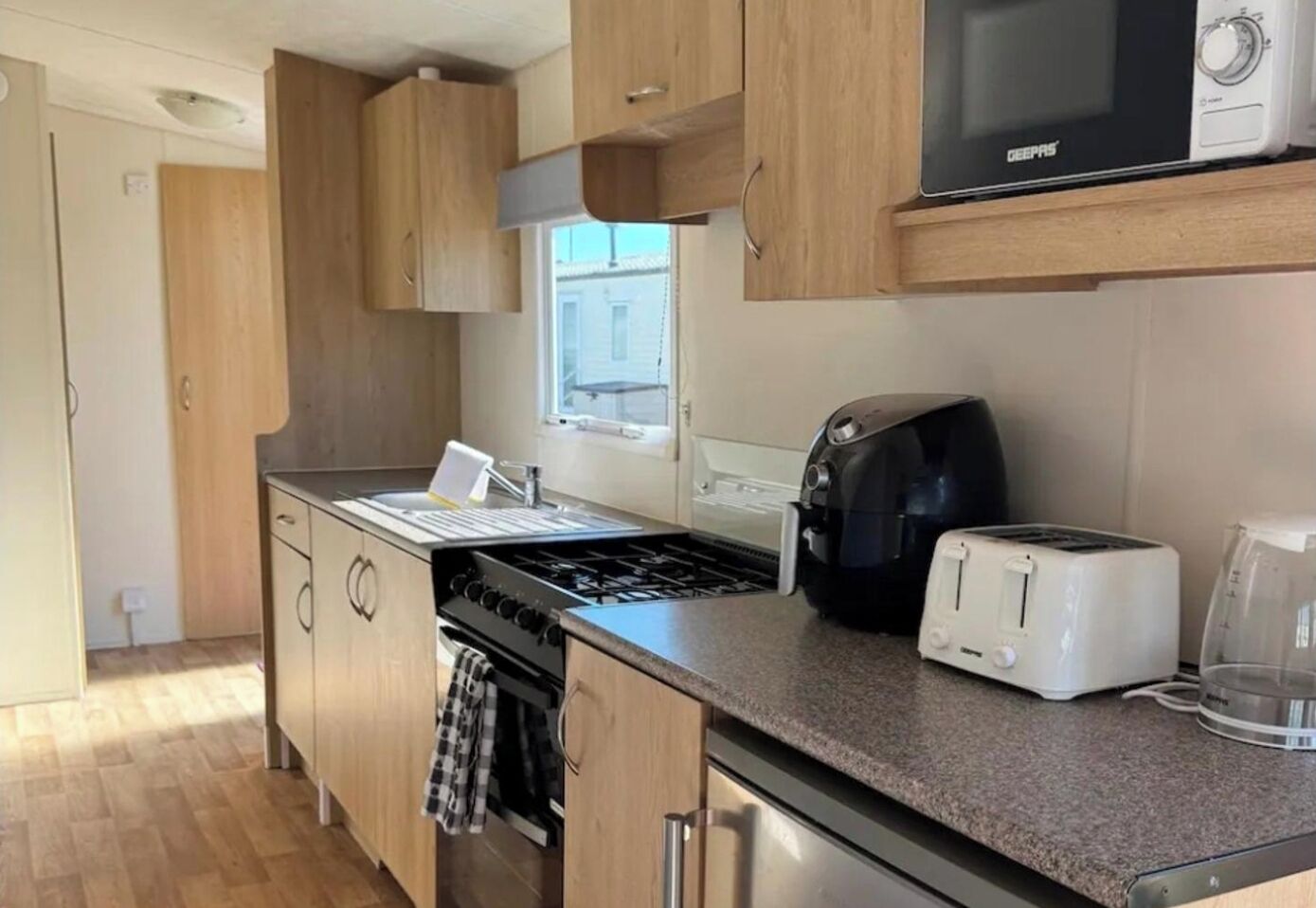 A compact kitchen with a gas stove, a microwave, a toaster, and a coffee maker.