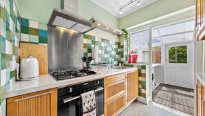 A modern kitchen with a gas stove, oven, and stainless steel range hood. - Cozy 3bd, Garden, Free Parking, M25,Bluewater (Dartford)