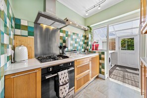 Eine moderne Küche mit Gasherd, Backofen und einer Edelstahl-Dunstabzugshaube.
