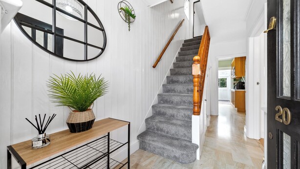 A staircase with a wooden handrail, a potted plant, and a metal shelf with a candle holder. - Cozy 3bd, Garden, Free Parking, M25,Bluewater (Dartford)