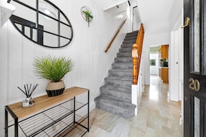 Eine Treppe mit Holzgeländer, einem Blumentopf und einem Metallregal mit Kerzenhalter.