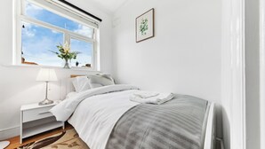 A bedroom with a bed, bedside table, lamp, window with view, and a framed picture on the wall. - Cozy 3bd, Garden, Free Parking, M25,Bluewater (Dartford)