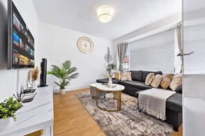 A modern living room with a flat-screen TV, a sofa, a coffee table, and a decorative wall clock.