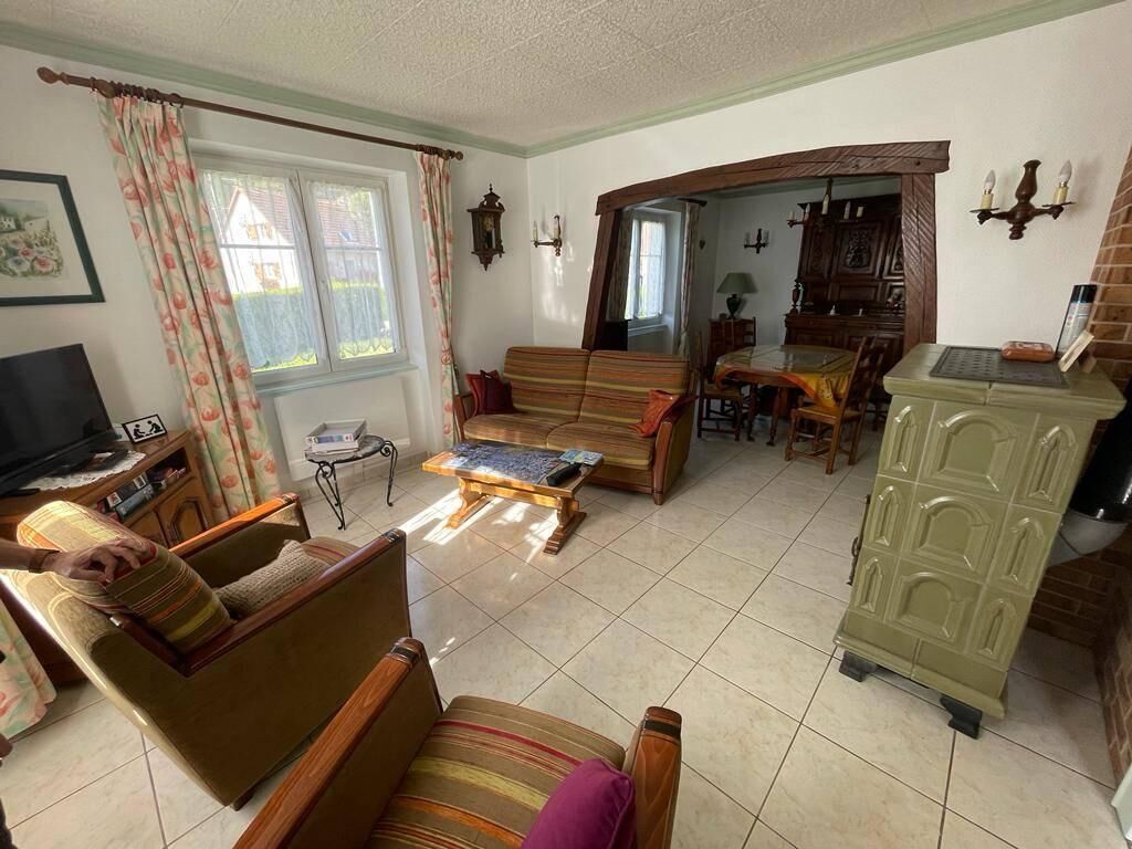 Ein Wohnzimmer mit Sofa, Sessel, Couchtisch und einem Essbereich mit Tisch und Stühlen.